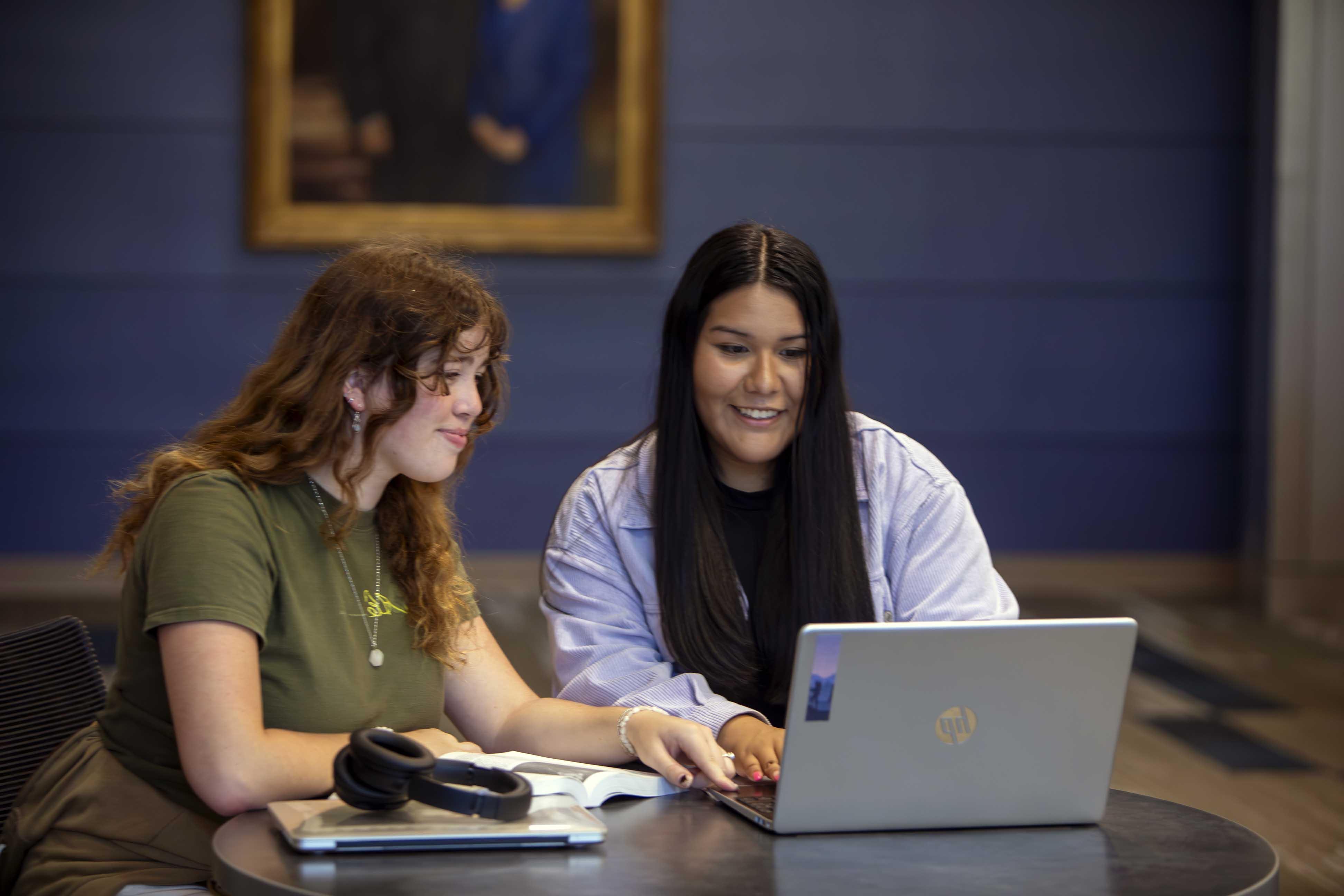 Two female students sharing a laptop, working